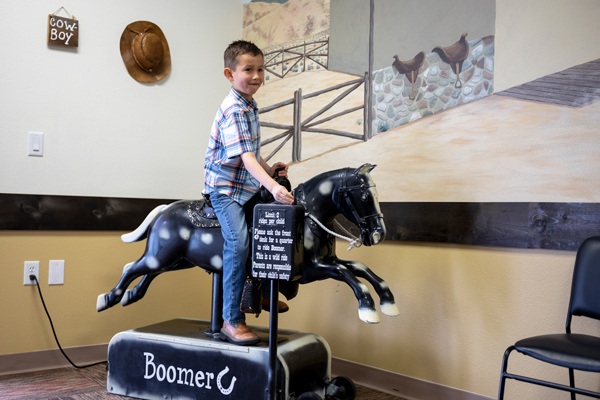 Child on mechanical horse ride indoors.