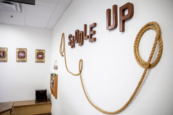 Room with 'Saddle Up' sign and rope decor.