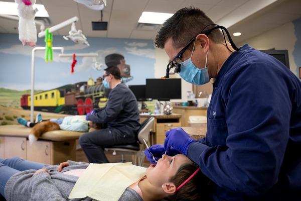 Dentist examining child's teeth in colorful office.