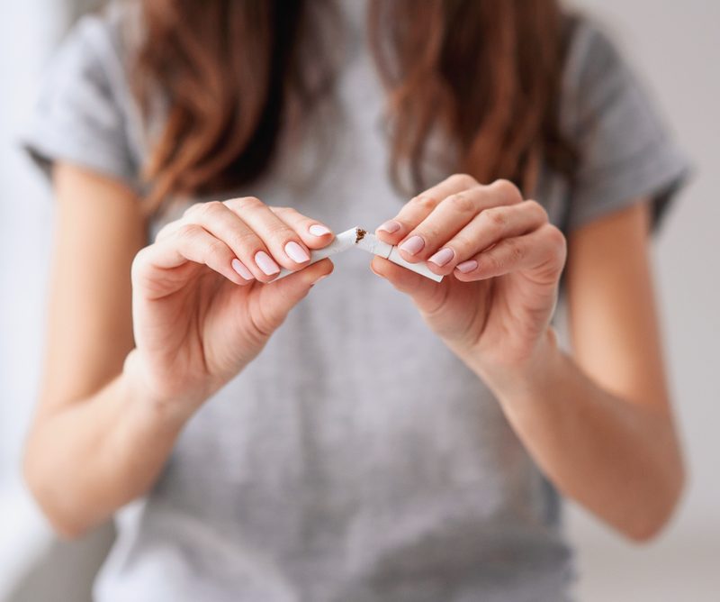 Person breaking a cigarette in half.