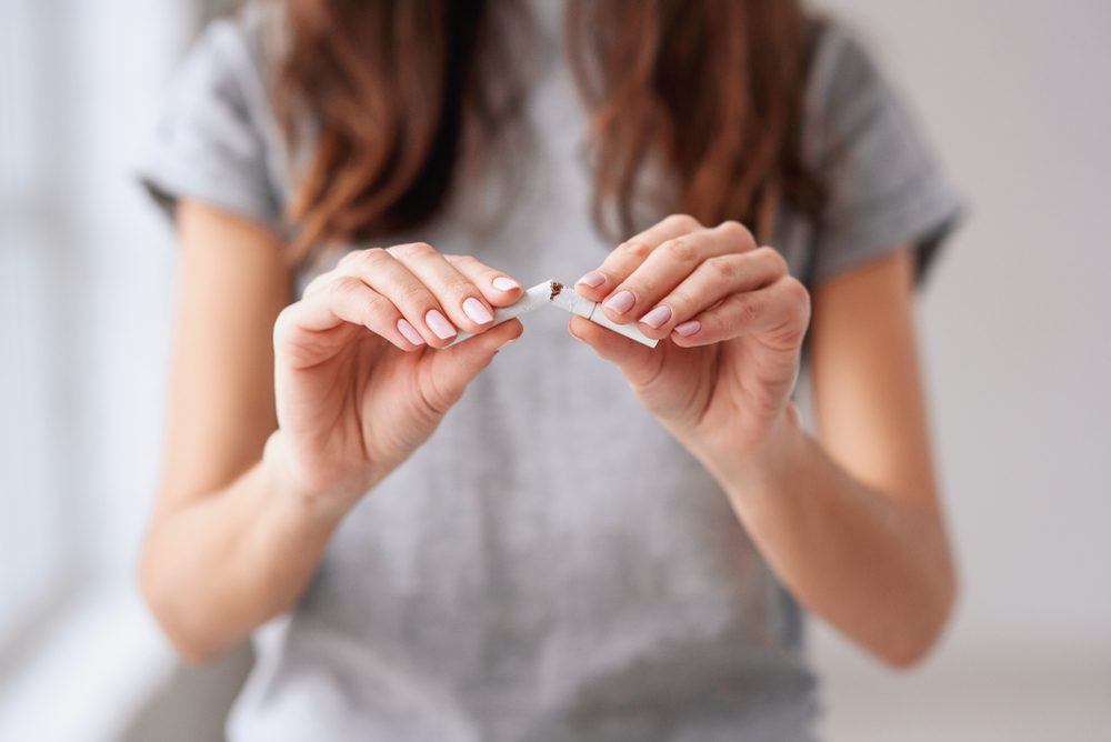 Person breaking a cigarette in half.