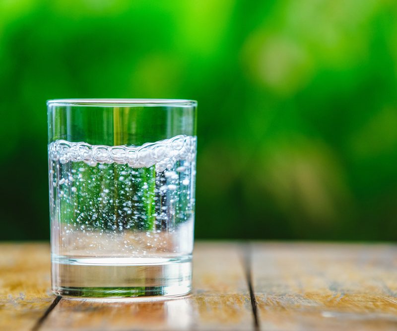Glass of sparkling water on wooden table.