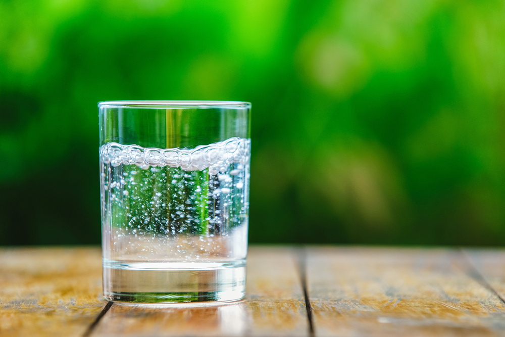 Glass of sparkling water on wooden table.