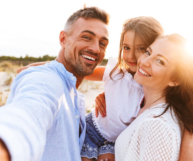 Happy family taking selfie on sunny beach