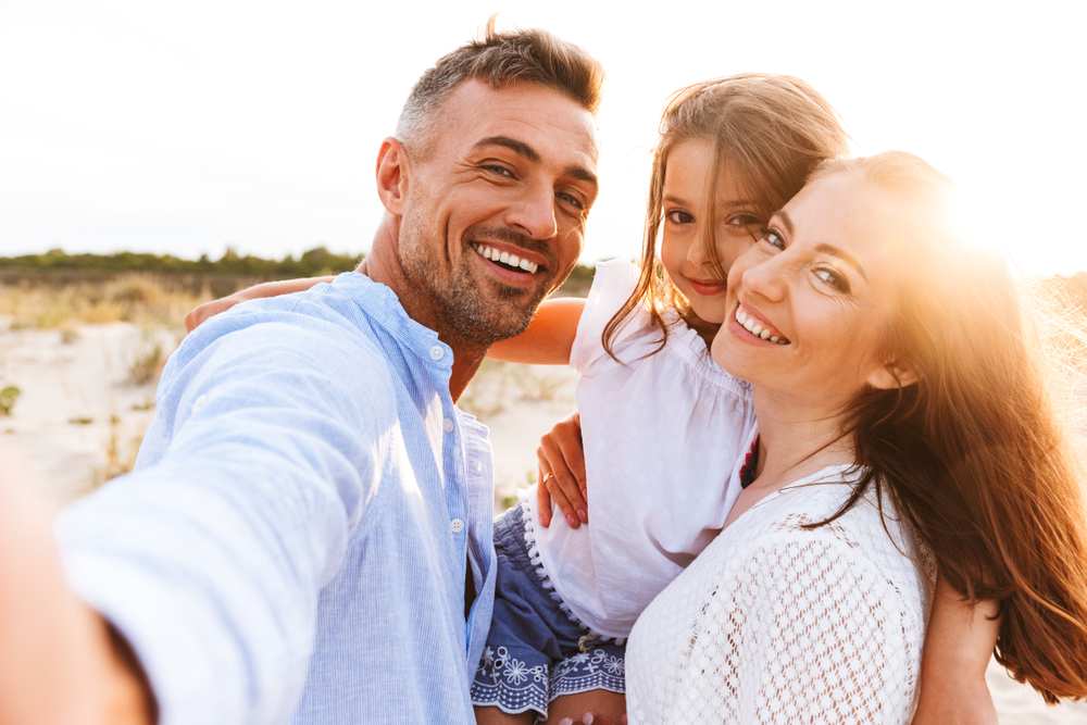 Happy family taking selfie on sunny beach