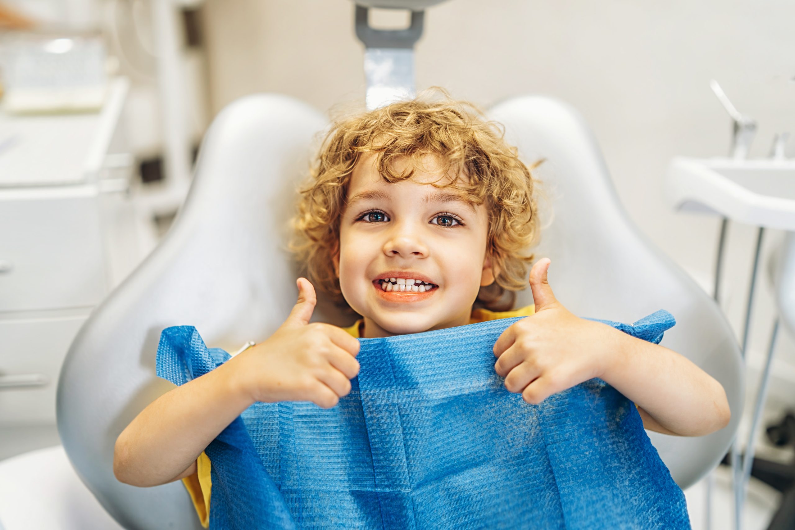 Happy child giving thumbs up at dentist