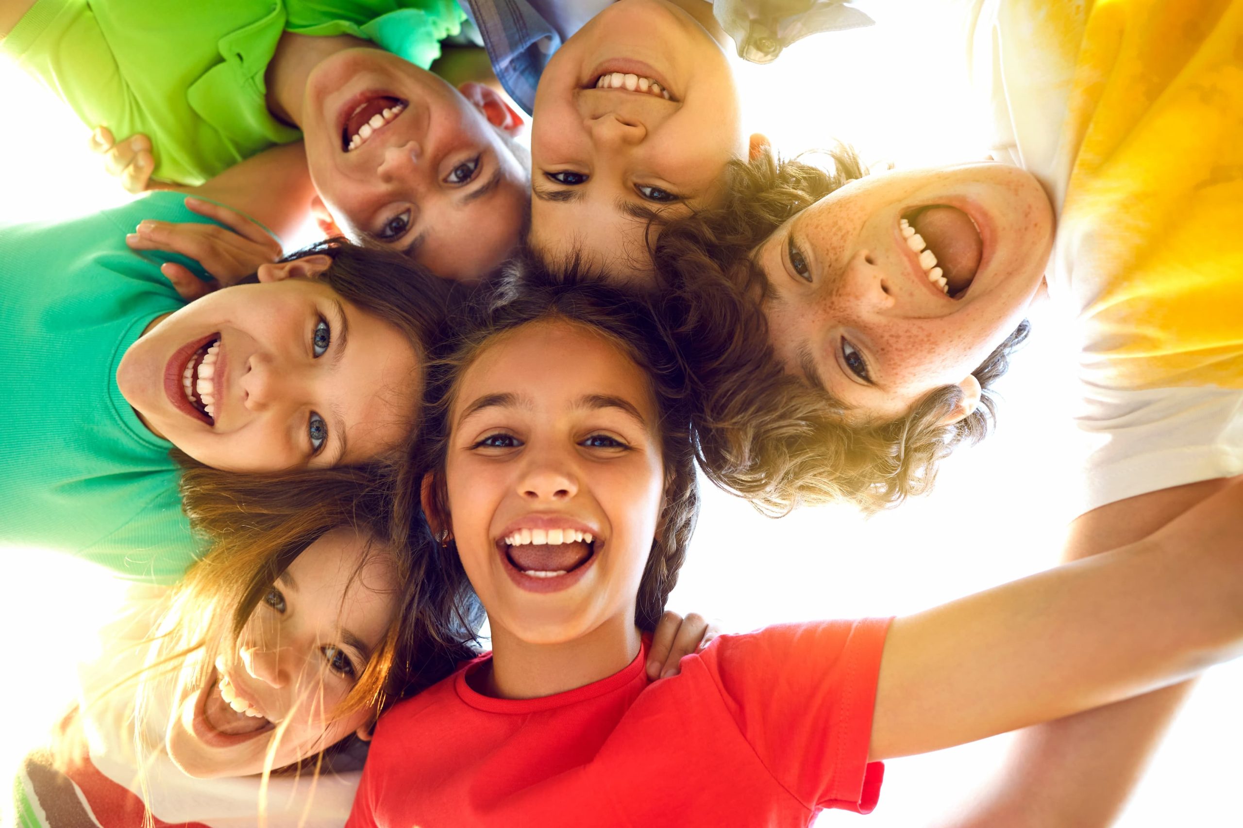 Happy kids smiling in a circle outdoors.